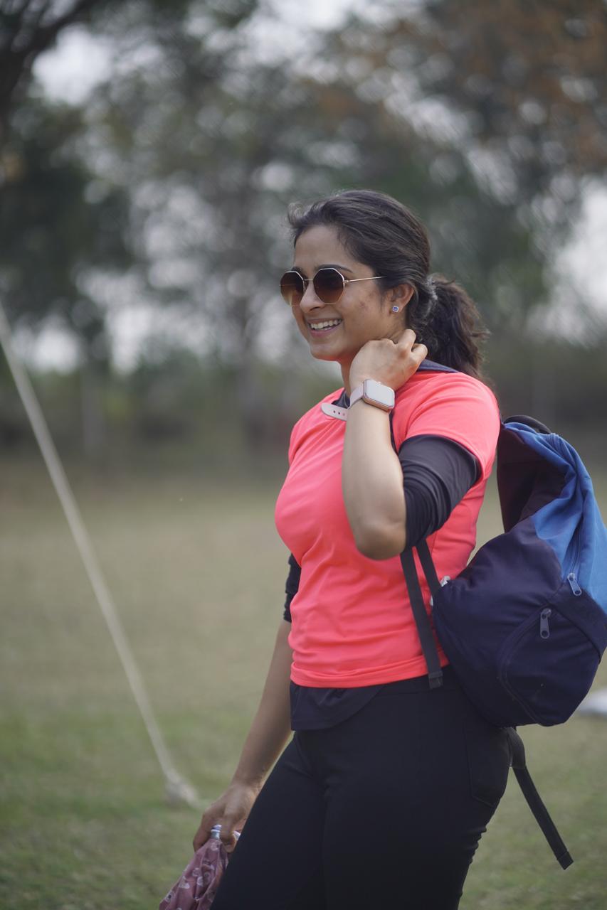 Dr. Vedika Gujarathi seated on a training field at golden hour, smiling at the camera.