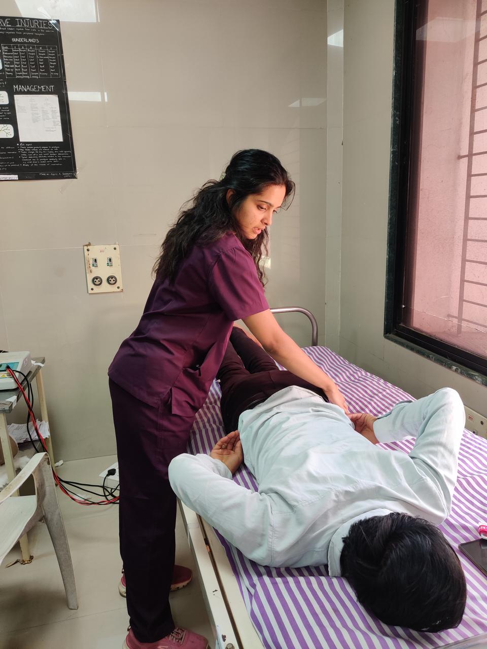 Dr. Vedika Gujarathi treating a patient in the clinic in maroon scrubs.